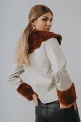 Campera de cuero napa color tiza, con cuello amplio y puños de lana marrón, de corte recto y manga larga.
