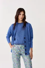 Cardigan azul con lurex, escote en V, manga larga, botones de pasta, terminaciones de rib y bolsillos delanteros.