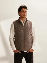 Chaleco de hombre confeccionado en 100% lana fina sin teñir, de diseño capitoneado con costuras romboidales, cuello alto y cierre frontal completo.