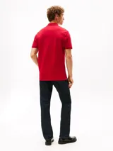 Chomba de corte regular Tommy Hilfiger, color rojo, confeccionada en algodón orgánico con un toque de elastano. Presenta cuello tipo chomba, cartera de dos botones, tejido piqué y logo de la marca bordado en el pecho.