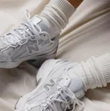 Championes urbanos New Balance modelo 740, color blanco con detalles plateados. Confeccionados en malla técnica y materiales sintéticos, presentan el logo N característico en los laterales y entresuela con tecnología ABZORB para mayor amortiguación.