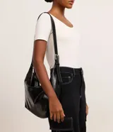 Bolso grande tipo hobo de material sintético negro, con correa de hombro ajustable y cierre de cremallera.