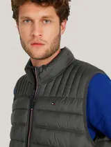 Chaleco acolchado de nailon en color gris, con cuello alto, cierre frontal de cremallera y bolsillos laterales con cierre. Presenta el logo de la marca bordado en el pecho.