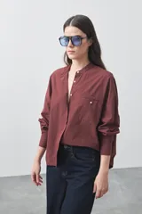 Camisa de manga larga en color celeste, con cuello mao y cierre frontal oculto. Presenta un diseño de silueta relajada con sisa caída y un bolsillo aplicado en el pecho.