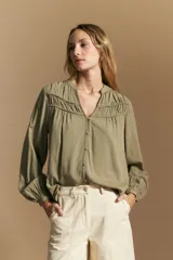 Camisa de manga larga color blanco, con cuello mao y escote en V. Presenta frunces en el canesú, cierre frontal con botones y mangas amplias con puños abotonados.