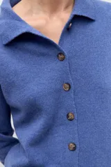 Cardigan de punto color azul con cuello polo y cierre frontal de botones. Presenta mangas largas con puños acanalados y un corte recto.