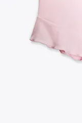 Top negro de cuello halter con lazada, escote recto y hombros descubiertos. Presenta un volante asimétrico en el lateral.