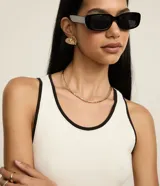 Musculosa de algodón rib, color blanco crudo, de corte regular y breteles anchos. Presenta un borde fino de color negro en el escote redondo y en las sisas.