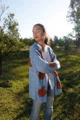 Cárdigan celeste pálido de lana merino con bordados florales color ladrillo hechos a mano.