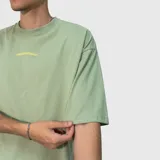 Remera de corte oversize color verde, con estampa tipográfica en color amarillo en la parte superior de la espalda.