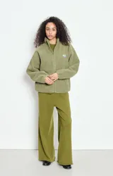 Campera de corderito con efecto shearling, color verde oliva, de corte holgado, cuello alto y cierre frontal completo. Presenta un pequeño parche con logo en el pecho.