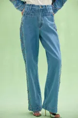 Pantalon de denim azul con corte recto y amplio, decorado con aplicaciones de pedrería formando un patrón de rombos en los laterales.