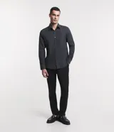 Camisa de manga larga confeccionada en tricolina de algodón, con cuello inglés, cierre frontal de botones y puños abotonados. Diseño liso y versátil.