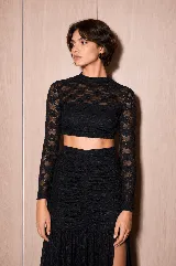 Top de encaje color negro, de silueta ajustada, con transparencias sutiles, cuello alto y mangas largas.