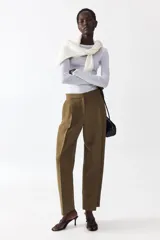 Pantalón de tiro alto de sarga color verde militar, con corte holgado y diseño barrel. Presenta pinzas y pliegues en la parte delantera y trasera, bolsillos al bies y bolsillos traseros decorativos.