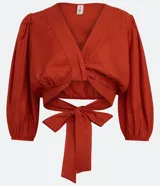 Blusa cropped roja de viscosa, con escote en V cruzado, mangas 3/4 abullonadas y lazo en la espalda.