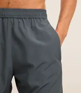 Bermuda deportiva masculina color verde oliva, confeccionada en poliéster y elastano. Posee cintura elástica con cordón interno ajustable y estampa reflectante en el lateral. Ideal para actividades deportivas.