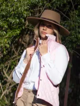 Chaleco capitoneado color rosa claro, con cuello alto, cierre frontal con botones a presión y logo bordado en el pecho.