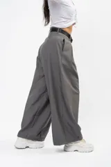 Pantalón de vestir gris de corte sastrero, con pinzas frontales, diseño de pierna ultra ancha y tiro medio.