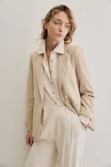 Blazer sastrero de lino color beige, de silueta relajada y líneas clásicas. Incorpora solapas tradicionales, cierre frontal de un botón y bolsillos de vivo.