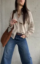 Camisa beige de inspiración boho con detalles bordados en mangas y puños, cuello en V con botones frontales y mangas largas abullonadas.