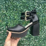 Zapatos de tacón alto con plataforma, confeccionados en cuero color marfil y marrón tostado, con taco ancho de madera y doble tira con hebillas metálicas ornamentadas en el empeine.