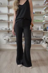Pantalón negro de corte acampanado, con costuras visibles y laterales de encaje negro con textura.