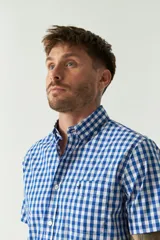 Camisa de manga corta con estampado de cuadros vichy en azul y blanco. Presenta cuello con botones, cierre frontal con botones y logo bordado en el pecho.