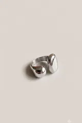 Anillo de metal plateado con diseño abierto y extremos abultados de formas orgánicas.