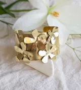 Brazalete ancho de bronce con apliques de flores.