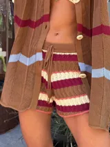 Short de tejido de punto con diseño de rayas horizontales en colores crema, bordó y celeste. Presenta cintura elástica con cordón ajustable y textura calada.