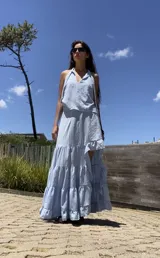 Pollera larga asimétrica de color celeste, con diseño de volados en capas y terminaciones con vuelo. Presenta un corte que permite dejar la pierna descubierta.