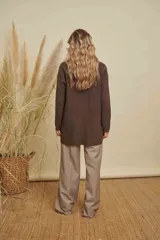 Buzo de punto color marrón, de corte holgado y largo, con cuello redondo, mangas largas y dos bolsillos frontales con detalle de desflecado en el borde superior.