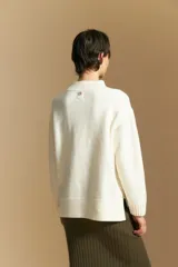 Polera de tejido de punto color blanco, con cuello alto acanalado, hombros caídos y detalle de costura vertical en el frente.