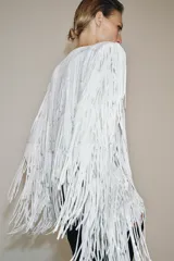 Chaqueta de cuello redondo y manga larga con hombreras, completamente cubierta de flecos con lentejuelas. Cuenta con forro interior y cierre frontal.
