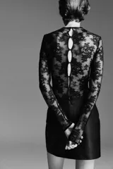 Pollera mini negra de tiro alto con acabado de efecto cuero. Presenta un corte recto y costura central en la espalda, con pinzas para estilizar la figura. La prenda está forrada.