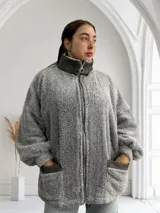 Camperón gris de tela tipo peluche con cierre frontal y bolsillos laterales.