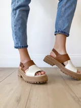 Sandalias de cuero color camel y crudo, con plataforma track y hebilla ajustable.