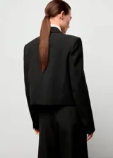Blazer corto de corte recto con cuello de solapa, cierre frontal de gancho y bolsillos de ribete. Presenta mangas largas con puños abotonados y forro interior.