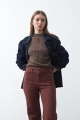 Pantalón de fit recto color beige, confeccionado en cotton spandex. Presenta costuras visibles y bordados decorativos en tono dorado/marrón claro. El ruedo del pantalón tiene un borde festoneado.