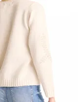 Buzo color beige de tejido suave con bordados florales de ramas y hojas en canutillos al tono en la parte delantera y mangas. Escote, puños y ruedo con terminación en rib acanalado.