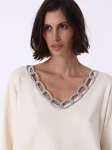 Sweater color crema de tejido de punto, con escote en V y detalle de cadena plateada con strass en el borde del escote.