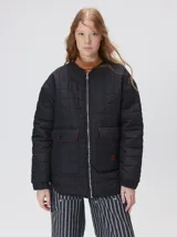 Campera reversible capitoneada con cierre frontal. Un lado es de color negro y el otro es de color beige, ambos con diseño acolchado. Cuenta con cuello redondo, mangas largas y bolsillos laterales.