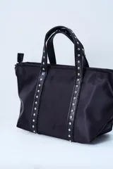 Bolso negro tipo tote bag con apliques de tachas plateadas en las asas y en los laterales.