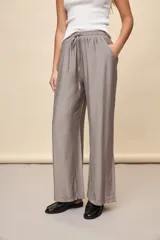 Pantalón gris de corte amplio y silueta fluida, con cintura elástica y cordón ajustable.