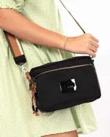Bandolera de nylon color negro con laterales en cuero, cierres metálicos, grifa de charol y detalles de cordones decorativos. Incluye correa regulable e intercambiable.