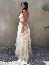 Vestido largo verde con diseño estampado tipo tie-dye y detalles dorados, de corte fluido, un solo hombro y diseño amplio.