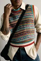 Chaleco de punto tejido en hilatura de algodón con diseño patchwork de patrones jacquard multicolores, cuello redondo y terminaciones en rib.