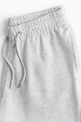 Pantalón de jogging gris claro en felpa de mezcla de algodón, con cintura elástica ajustable con cordón, bolsillos laterales y puños acanalados. Corte estándar.