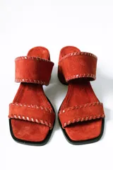 Sandalias tipo mule de taco medio, confeccionadas en cuero gamuzado color terracota. Presentan dos tiras anchas con detalles de costuras pespunteadas en los bordes y taco cuadrado estable.